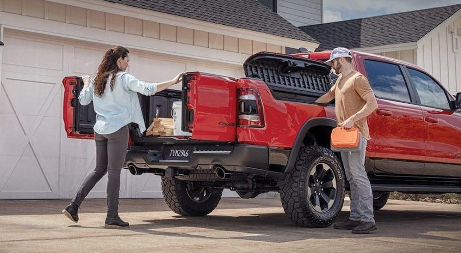A man and woman load items into a Ram 1500 pickup truck bed.