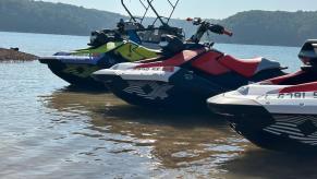 Jet skis and PWCs sit by the waters edge, waiting for a day of jet skiing.