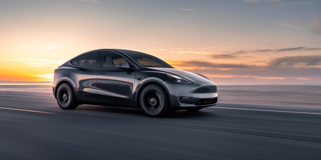 A black 2023 Tesla Model Y small electric SUV is driving on the road.