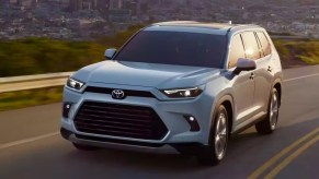 A white 2024 Toyota Grand Highlander is driving on the road.