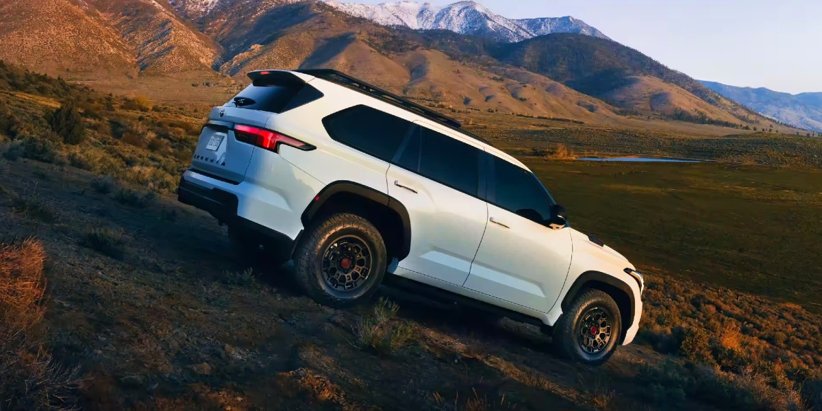 A white 2024 Toyota Sequoia full-size SUV is driving off-road.