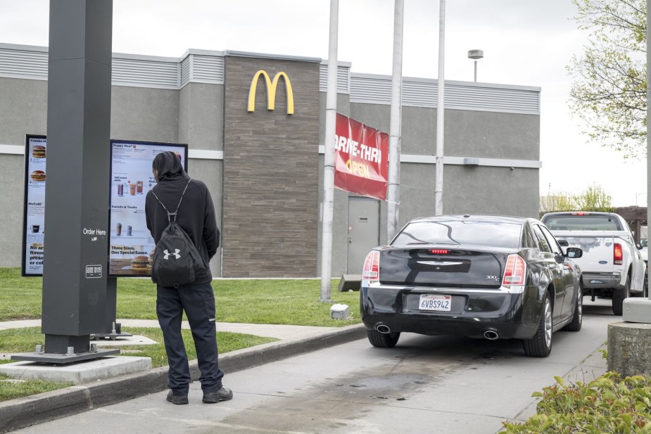 Walking man orders from a McDonald's restaurant drive-through lane.