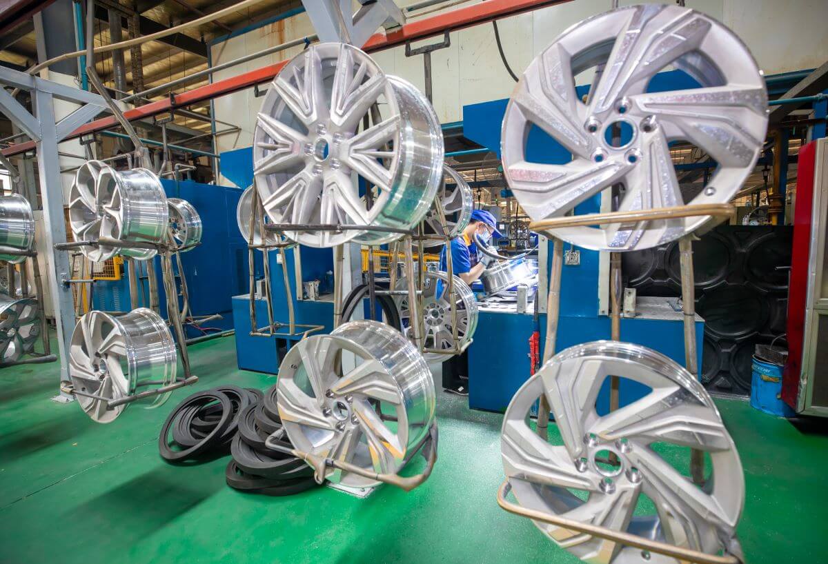 An energy vehicle workshop in Yuncheng, China, where workers are working on an order of aluminum alloy car wheels