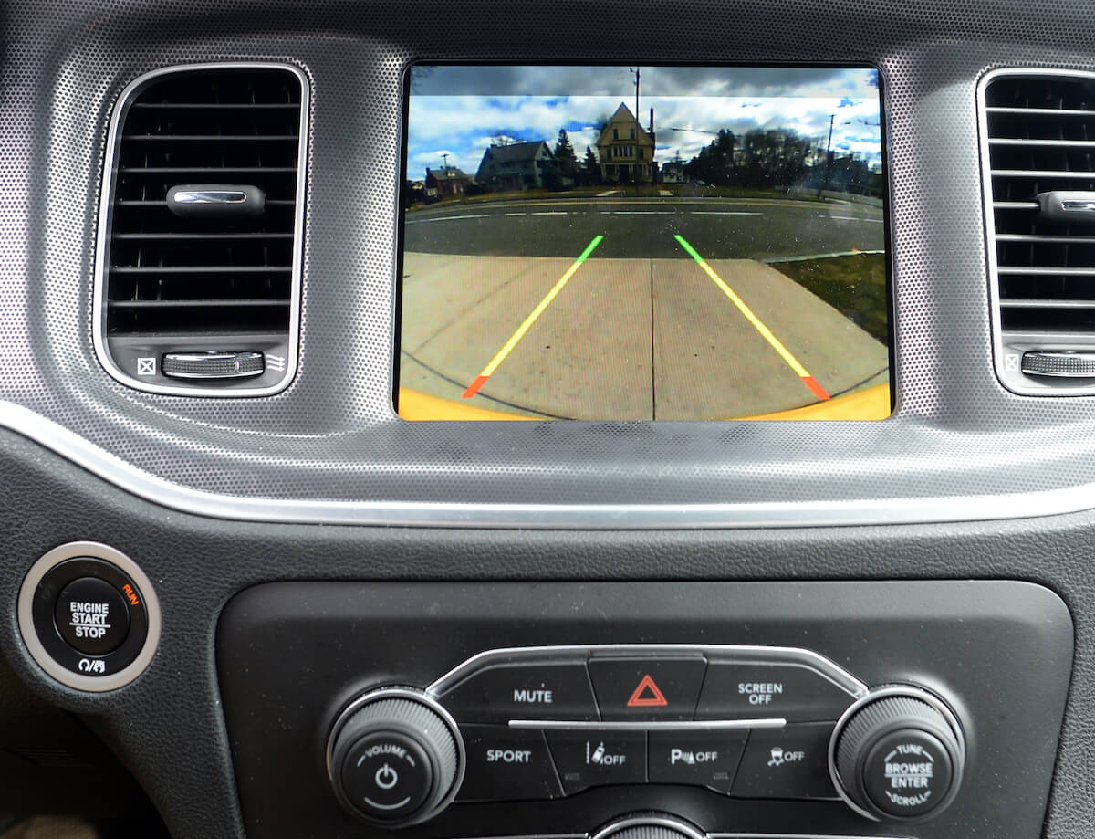 A small rear-facing camera installed on the back of a car, just above the license plate, providing a wide-angle view of the area behind the vehicle. This camera assists the driver in parking and reversing by displaying the live video feed on the car's infotainment screen, enhancing safety and convenience.