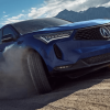 A 2024 Acura RDX compact luxury SUV model driving on off-road dirt as its tires spin up dust clouds