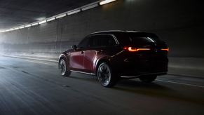 A rear shot of illuminated taillights on a 2024 Mazda CX-90 full-size SUV exiting into the light from a dark tunnel