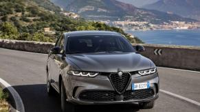 A 2024 Alfa Romeo Tonale plug-in hybrid compact SUV model driving on a scenic highway near seaside towns