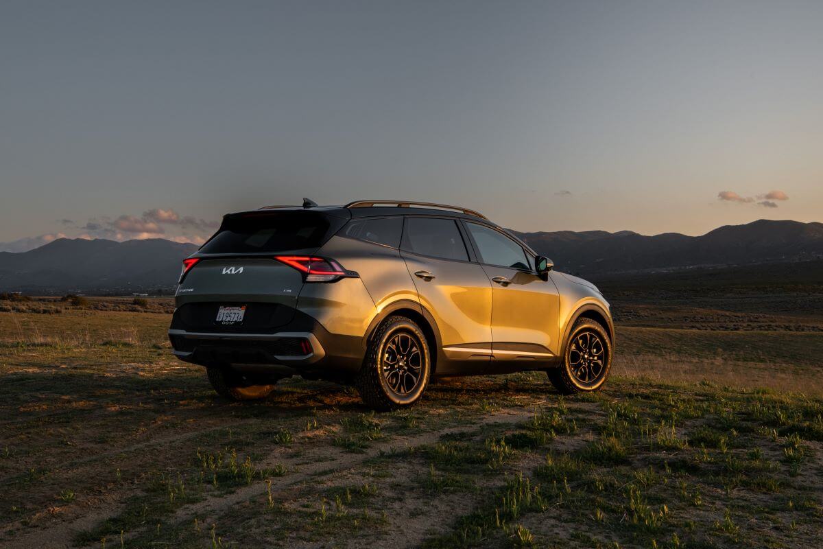A rear shot of the trunk and taillights on a 2024 Kia Sportage X-Pro compact SUV model as the sun sets in the wild