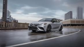 A 2024 Toyota Camry XSE AWD midsize sedan model driving on a wet highway road under dark clouds