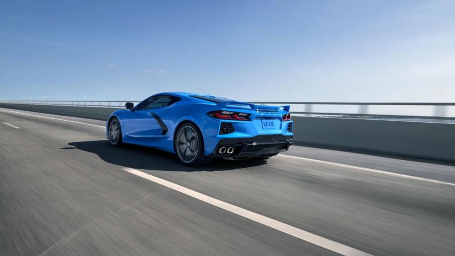 A 2024 Chevy Corvette Stingray performance sports car coupe model in Rapid Blue driving on a highway bridge
