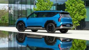 The all-electric 2024 Kia EV9 midsize SUV model parked on a plaza with a reflection off the water