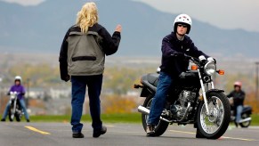 An instructor coaches a student rider on a course used for motorcycle classes.