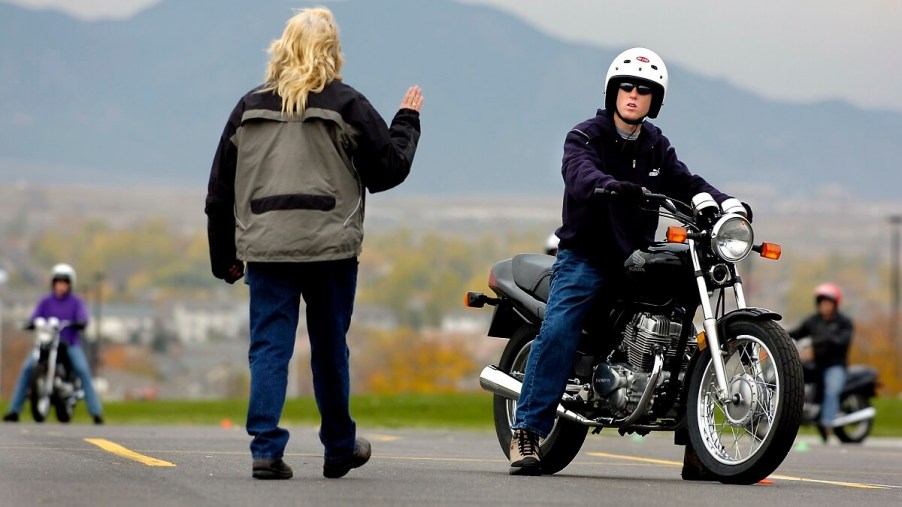 An instructor coaches a student rider on a course used for motorcycle classes.