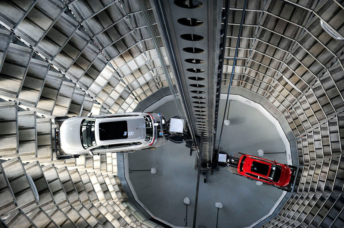 A machine organizes Volkswagen cars in a circular parking garage.