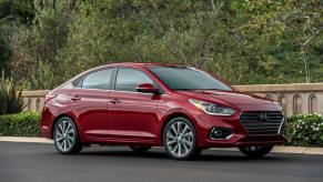 A 2022 Hyundai Accent subcompact sedan model parked next to bushes and a stone border