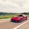 A 2024 Maserati GranTurismo Trofeo grand tourer model driving past farm houses and fields in Italy