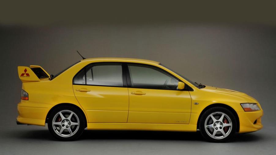 A side profile promotional shot of a 2003 Mitsubishi Lancer Evolution VIII sports sedan with a rear spoiler