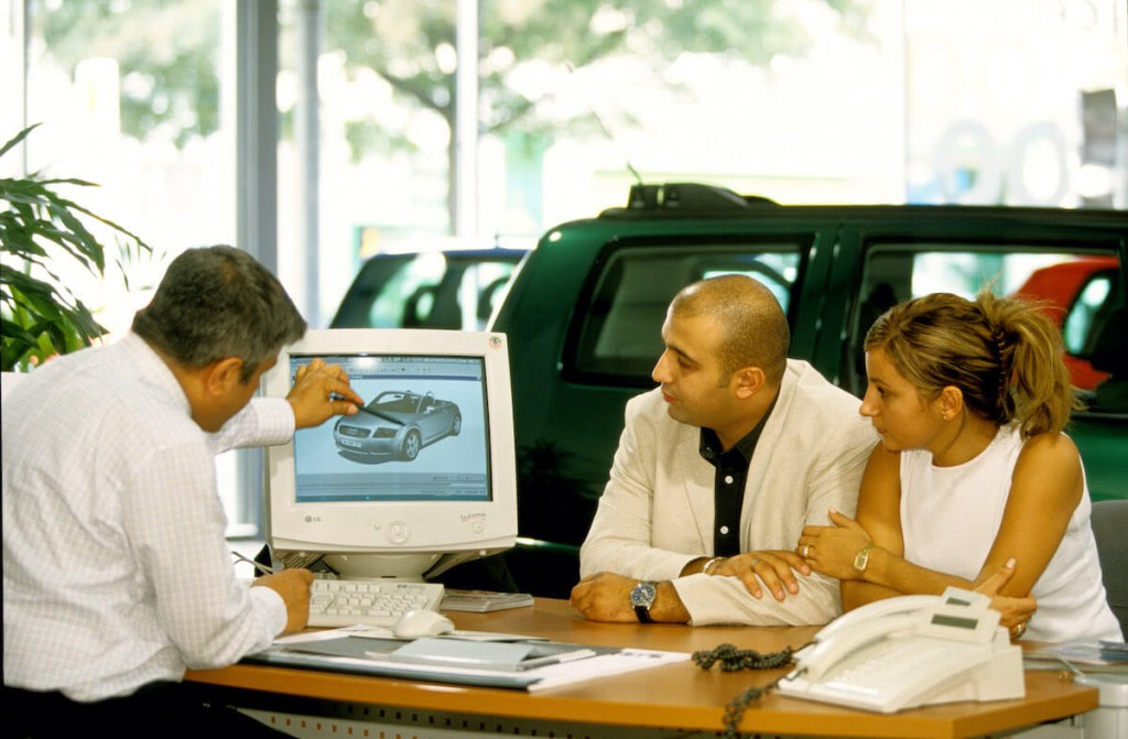 A turkish salesperson talks to his customers about an Audi, likely providing various car buying tips during the process