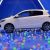 A side profile shot of a 2024 Mitsubishi Mirage subcompact hatchback model surrounded by multi-colored balls