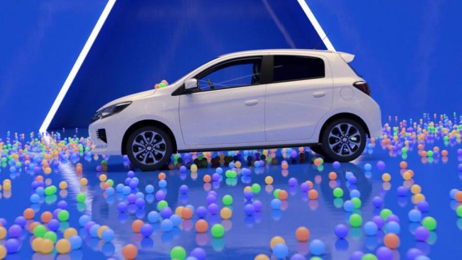 A side profile shot of a 2024 Mitsubishi Mirage subcompact hatchback model surrounded by multi-colored balls