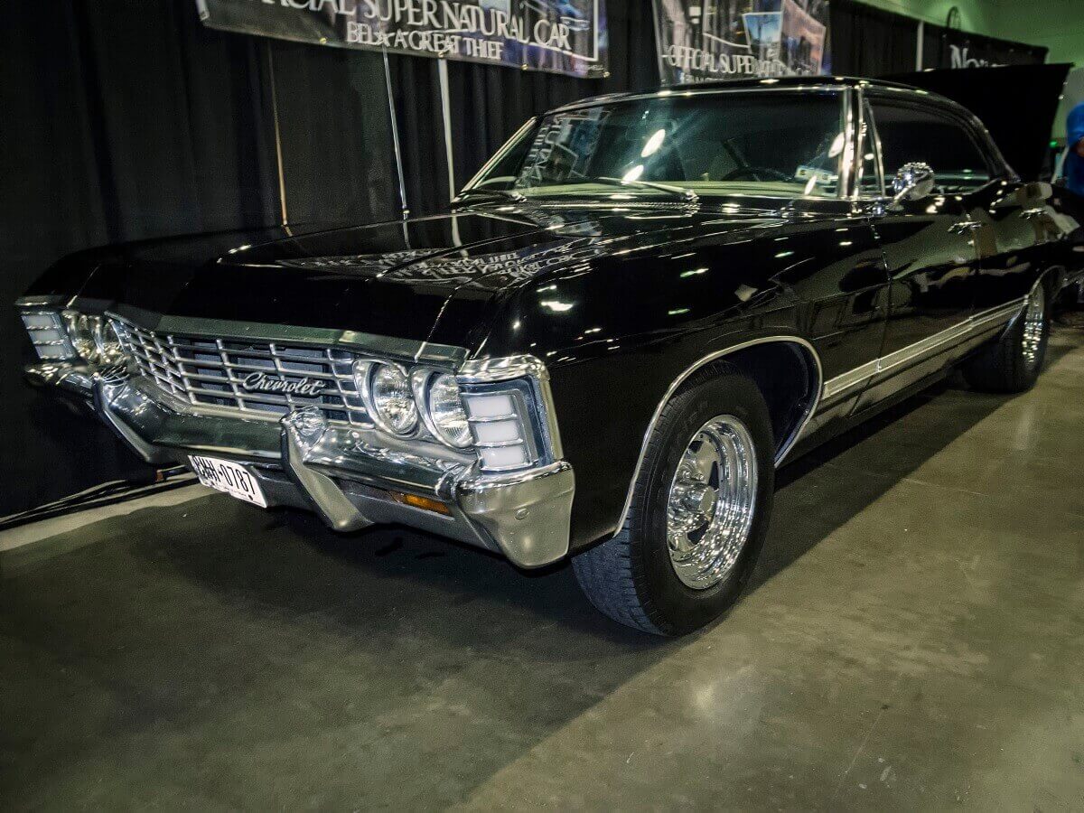 Dean Winchester's black 1967 Chevrolet Impala from 'Supernatural' sits at a car exhibit in a comic book showcase.