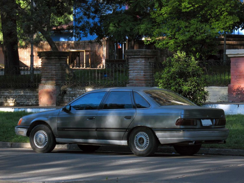 1986 Ford Taurus parked beneath trees on a residential street.