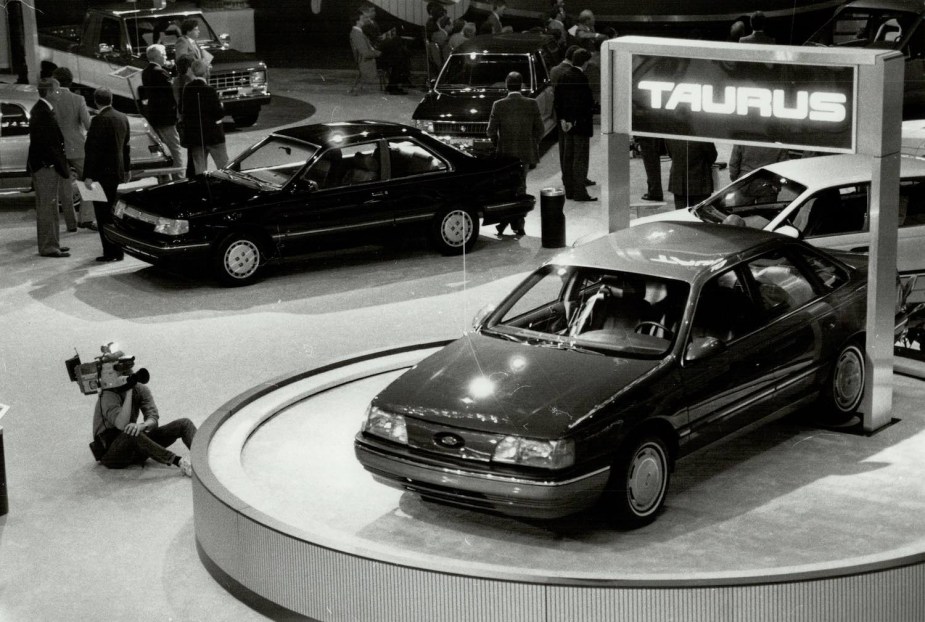 Black and white image of the 1986 Ford Taurus parked on a pedestal at a car show.