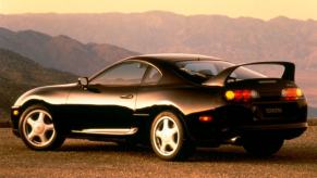 A rear/side profile shot of a 1994-1996 Toyota Supra sports car coupe model parked near a mountain range