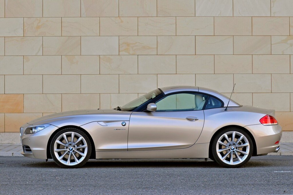 A gold E89 BMW Z4 convertible keeps its top up and shows off its side profile.