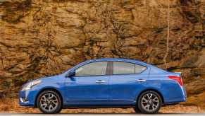 A blue 2016 Nissan Versa compact sedan parked against a rock wall