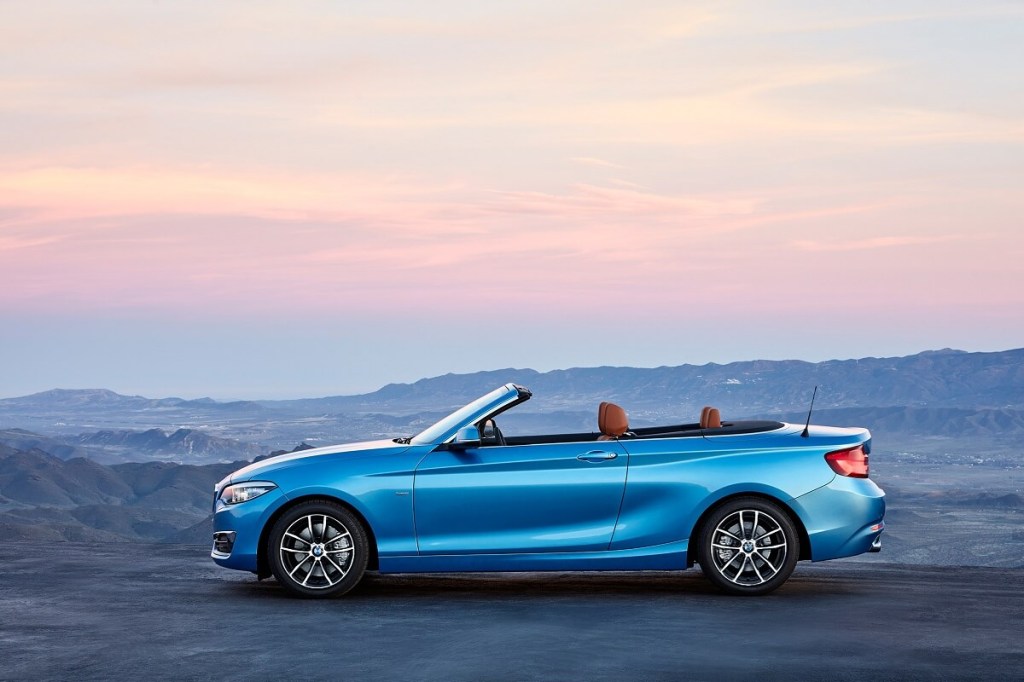 A blue F22 2018 BMW 2 Series convertible parks under a sunset.
