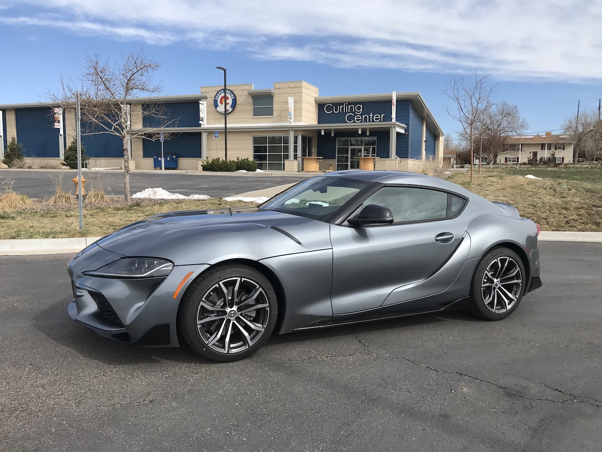 The front corner view of the 2021 Toyota Supra 2.0 next to a Curling Center