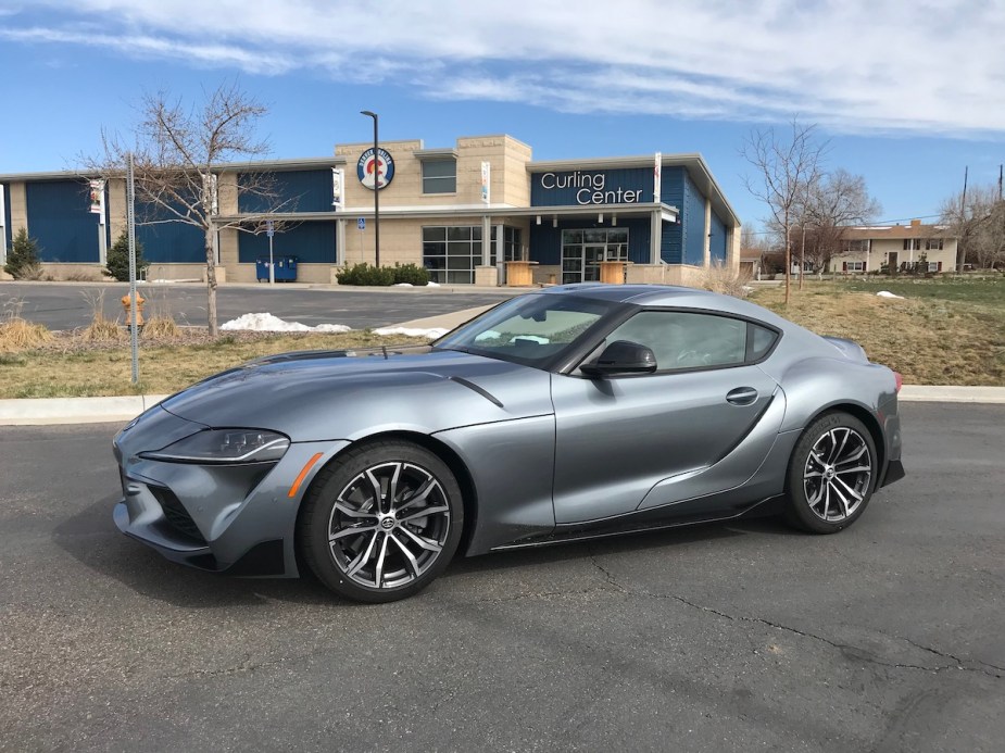 The front corner view of the 2021 Toyota Supra 2.0 next to a Curling Center