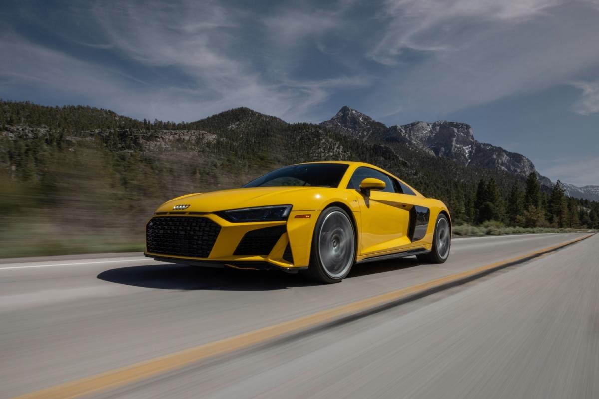 A yellow Audi R8 driving down an open road.