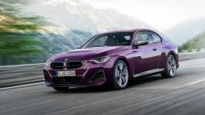 A purple 2023 BMW 2 Series, smaller than the higher-tier 3 Series, drives on a mountain road.