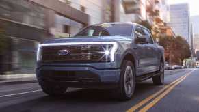 A 2023 Ford F-150 Lightning driving down a city street.