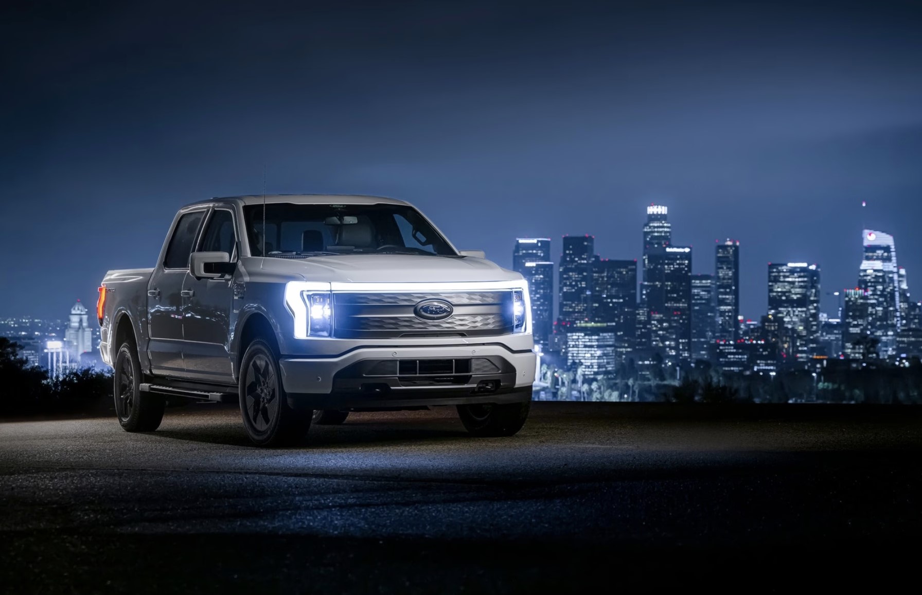 The 2023 Ford F-150 Lightning parked near a city at night