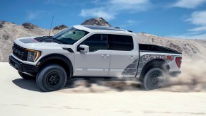 2023 Ford F-150 Raptor R in white driving down a dusty road in the desert. The Ford F-150 Raptor's price is a huge leap from the next trim.