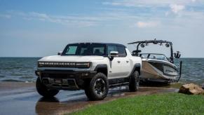 A 2023 GMC Hummer EV Edition 1 full-size all-electric pickup truck model towing a boat out of the water