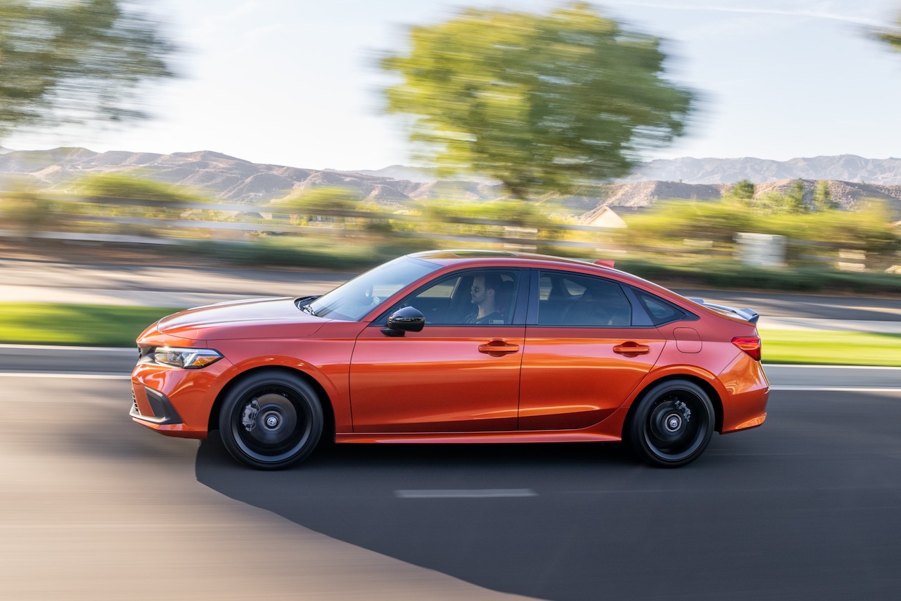 The 2023 Honda Civic Si in orange speeding down a suburban street. It's known for its performance, but the Honda Accord Sport might be a better pick.