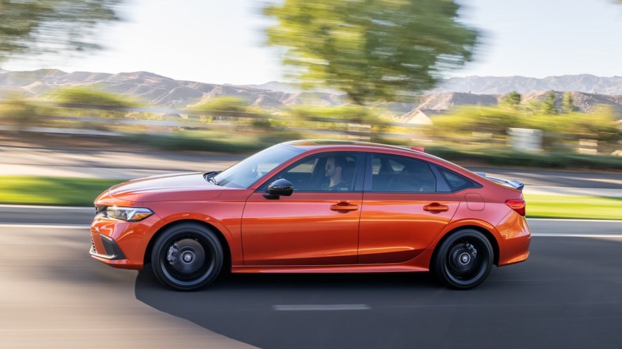 The 2023 Honda Civic Si in orange speeding down a suburban street. It's known for its performance, but the Honda Accord Sport might be a better pick.
