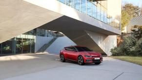 The top Kia EV – the 2023 Kia EV6 – pictured in red parked underneath a modern building.