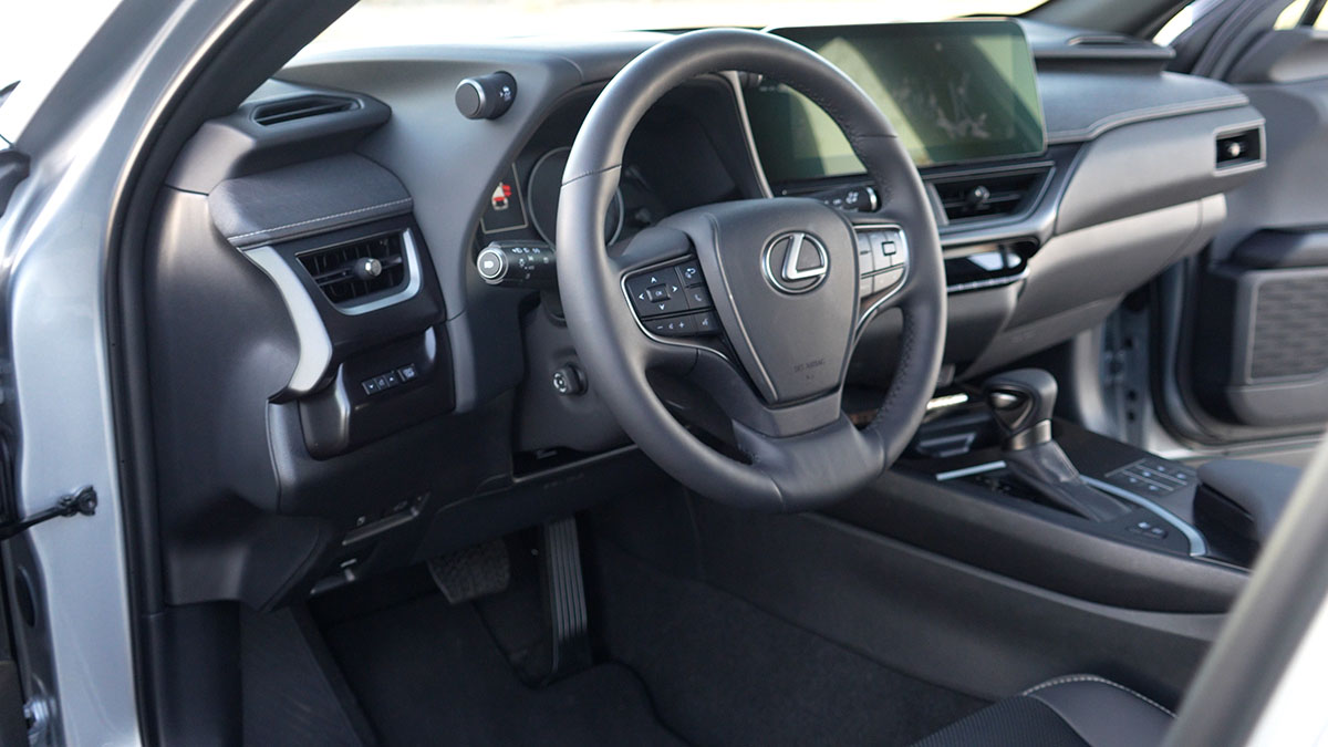 Black leather interior steering wheel and dash view of 2023 Lexus UX 250h compact cheap luxury affordable hybrid SUV