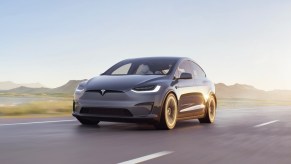 A gray 2023 Tesla Model X is driving on the road.