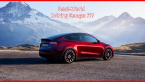 A red 2023 Tesla Model Y small electric SUV is parked facing the mountains.