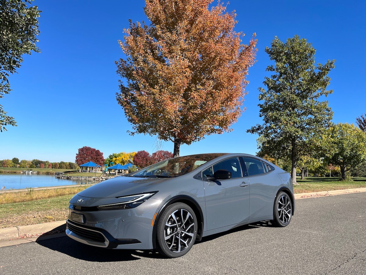 A front corner view of the 2023 Toyota Prius Prime next to a tree