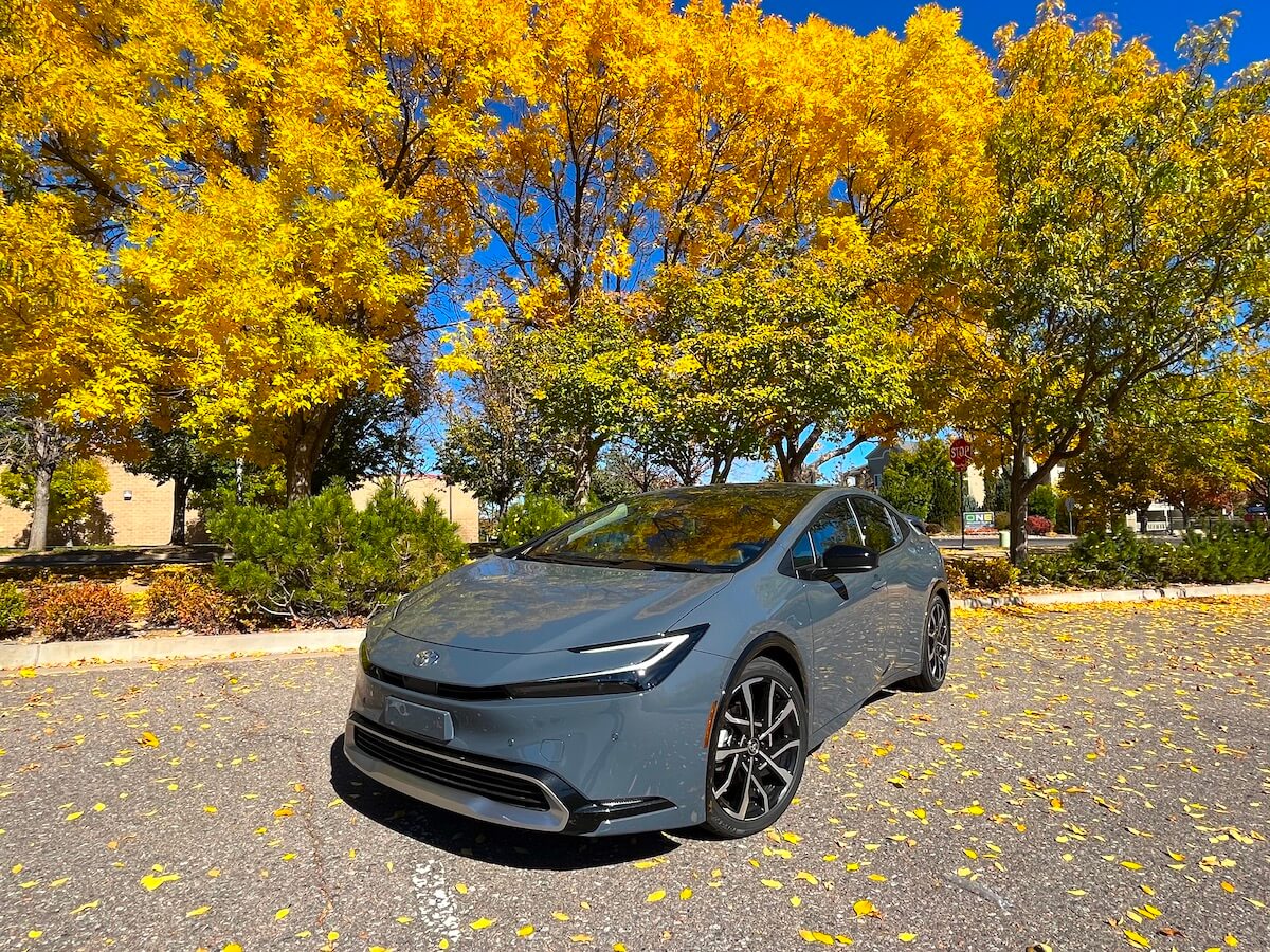 The 2023 Toyota Prius Prime parked in front of colorful trees.
