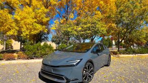 The 2023 Toyota Prius Prime parked in front of colorful trees.