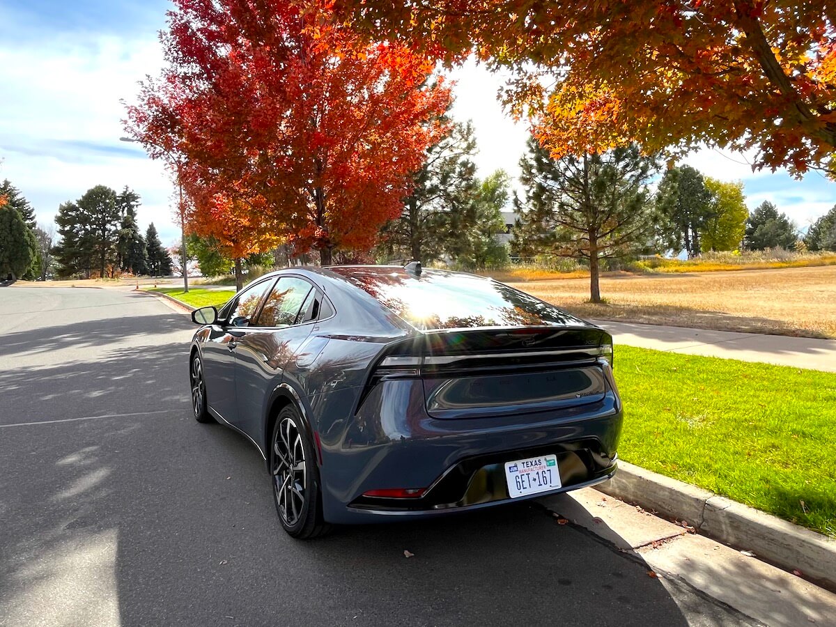 A rear view of the 2023 Toyota Prius Prime next to trees