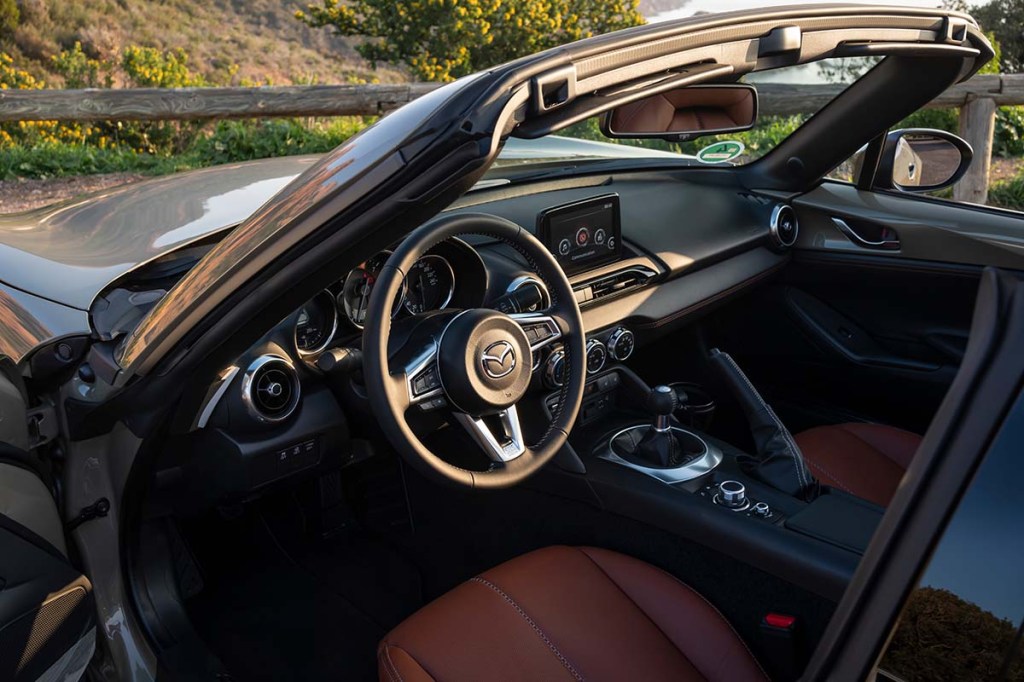 Interior view of driver's side in a 2023 Mazda MX-5 Miata parked at sunset